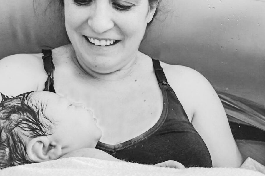 Stef and Jubilee The author smiling while holding her newborn daughter in the birthing tub